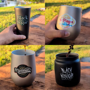 A collage of four images shows hands holding various metallic cups. Each cup features diverse coffee-themed designs and labels with vibrant colors, set against a grassy background. Coffee beans are seen being poured in one cup, and coffee is being poured into another, conveying a theme of enjoyment and relaxation.
